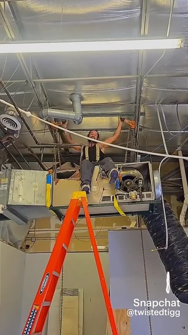 Technician on a ladder working on overhead piping